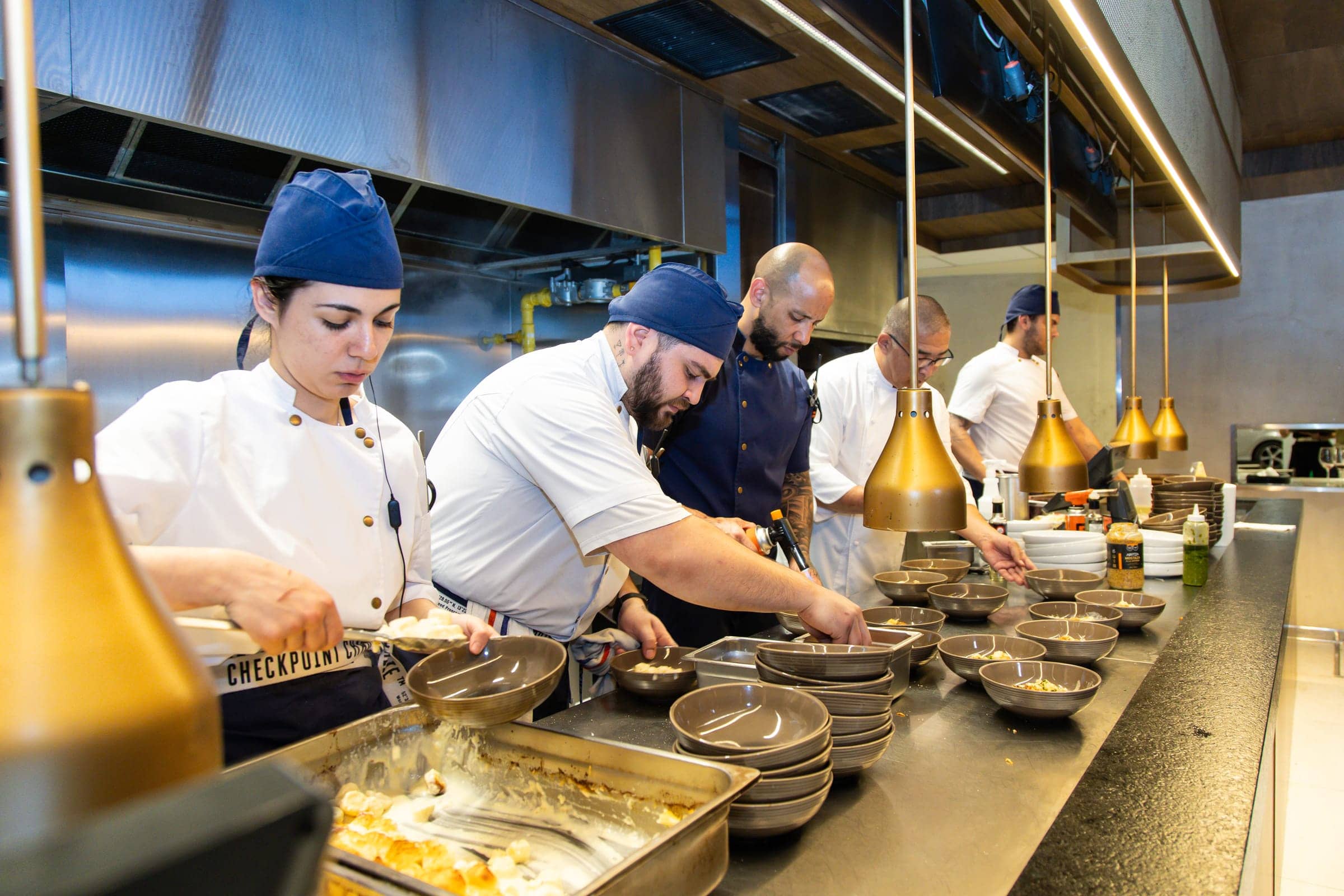 Brigada de cocina sirviendo en línea decenas de platos para un evento
