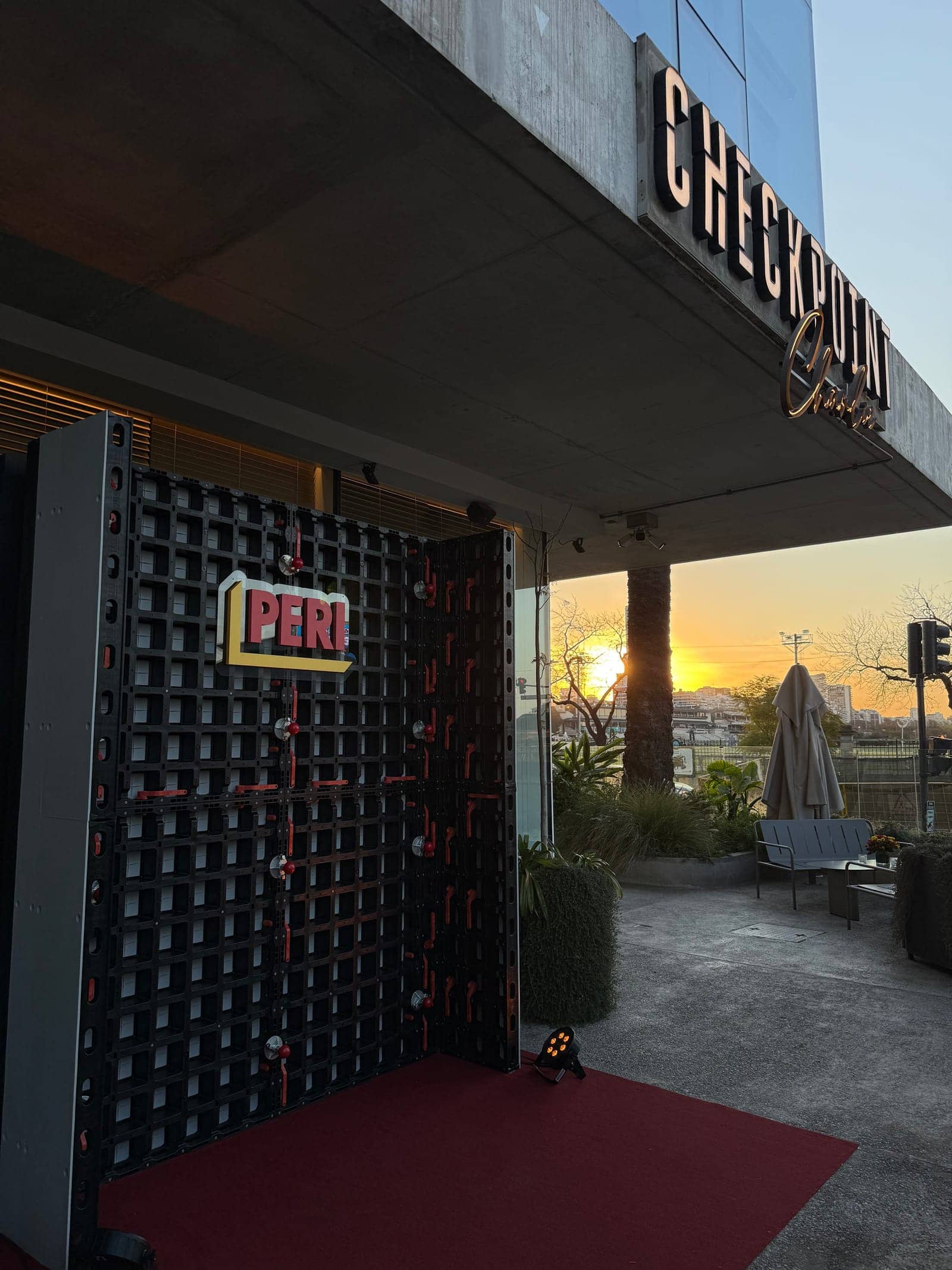 Photocall con alfombra roja en la entrada, bajo el cartel de Checkpoint Charlie, al atardecer