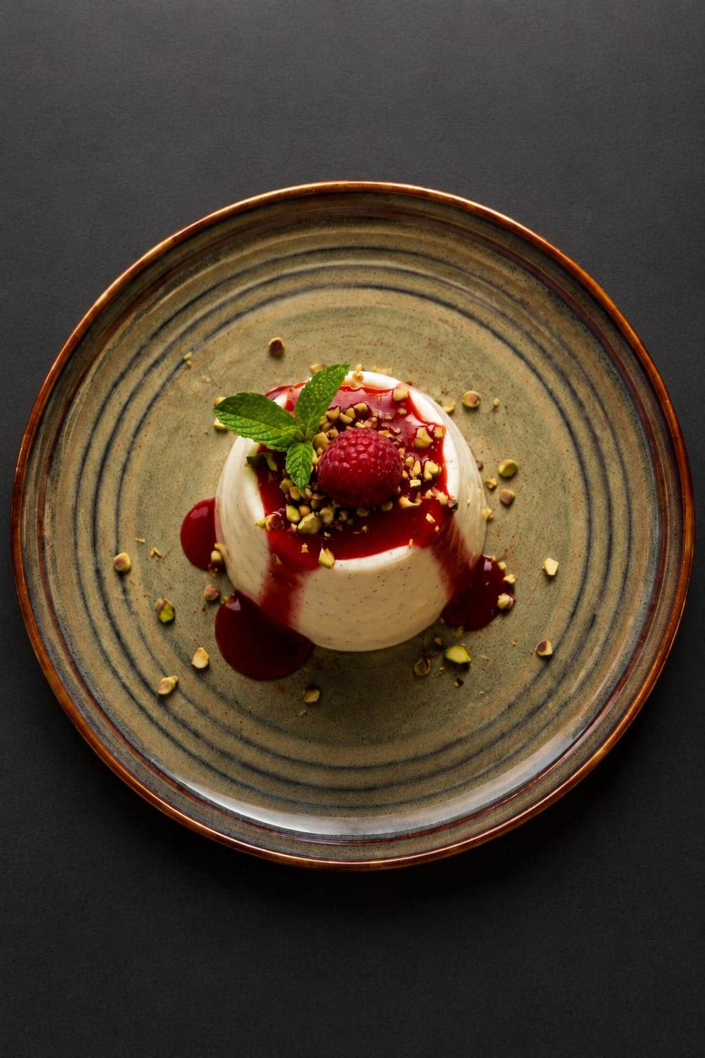 Pannacotta con coulis de frutos rojos, frambuesa, menta y pistachos
