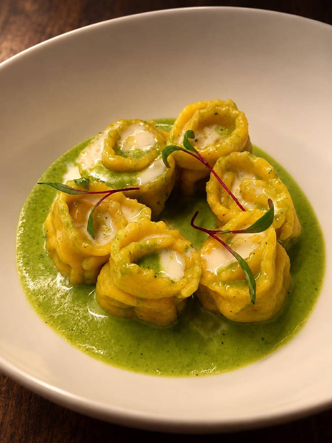 Ravioli di vitello sobre salsa verde de hierbas, con brotes