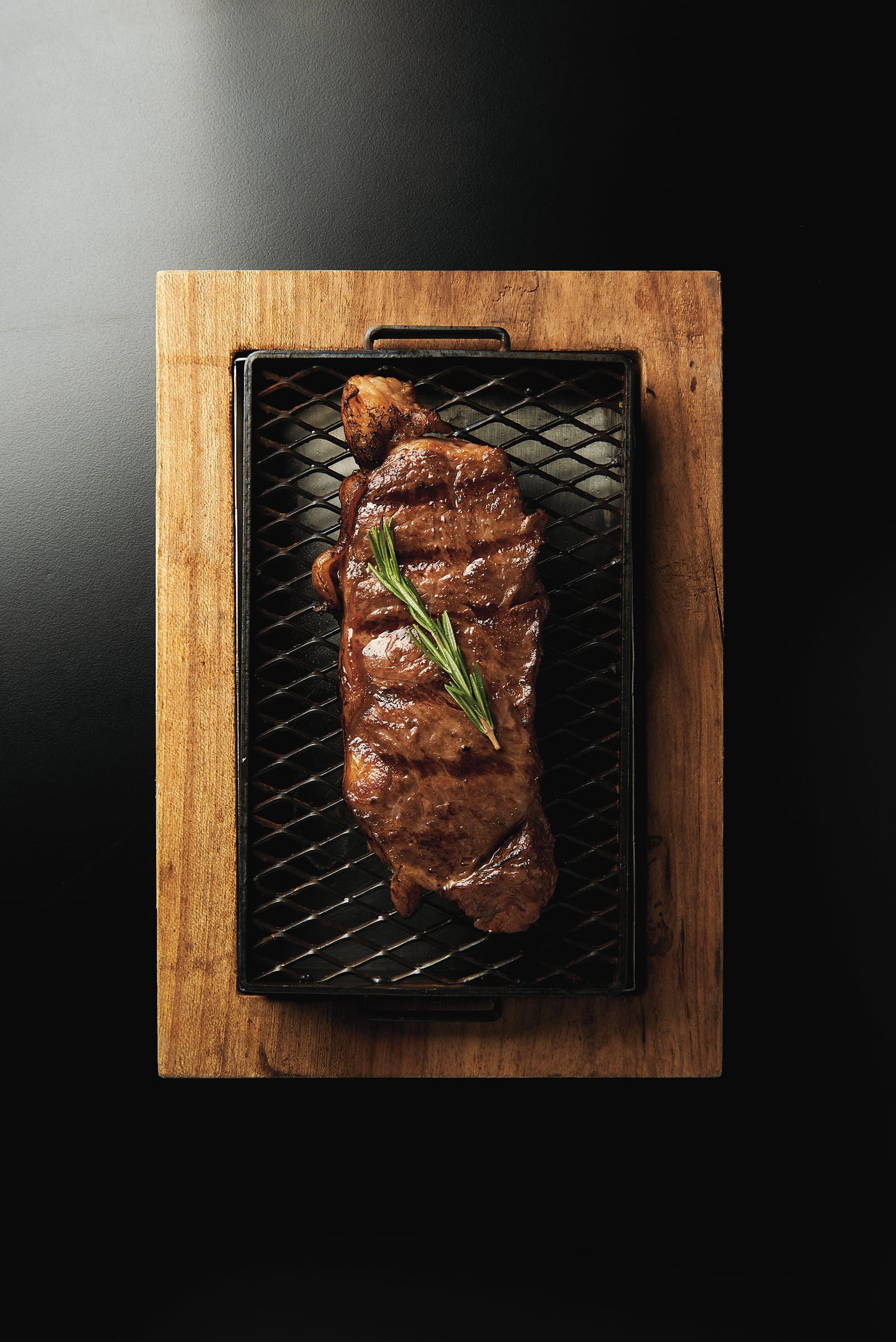 Corte a la parrilla sobre tabla de madera con romero