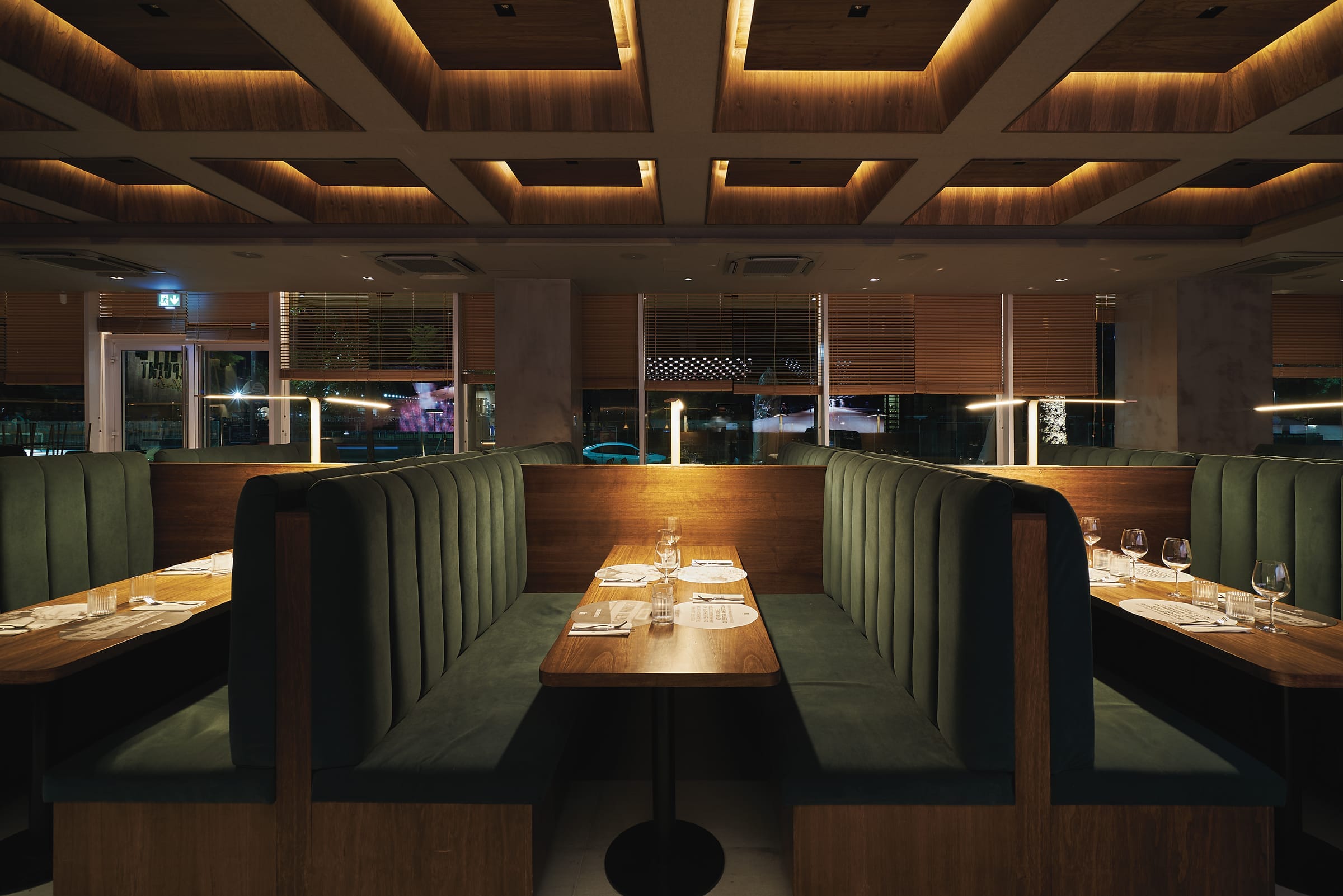 Salón principal con boxes tapizados en verde y cielorraso de madera iluminado